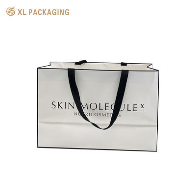 Custom branded luxury matte white coated art paper gift bag with wide black woven ribbon handle for cosmetic retail